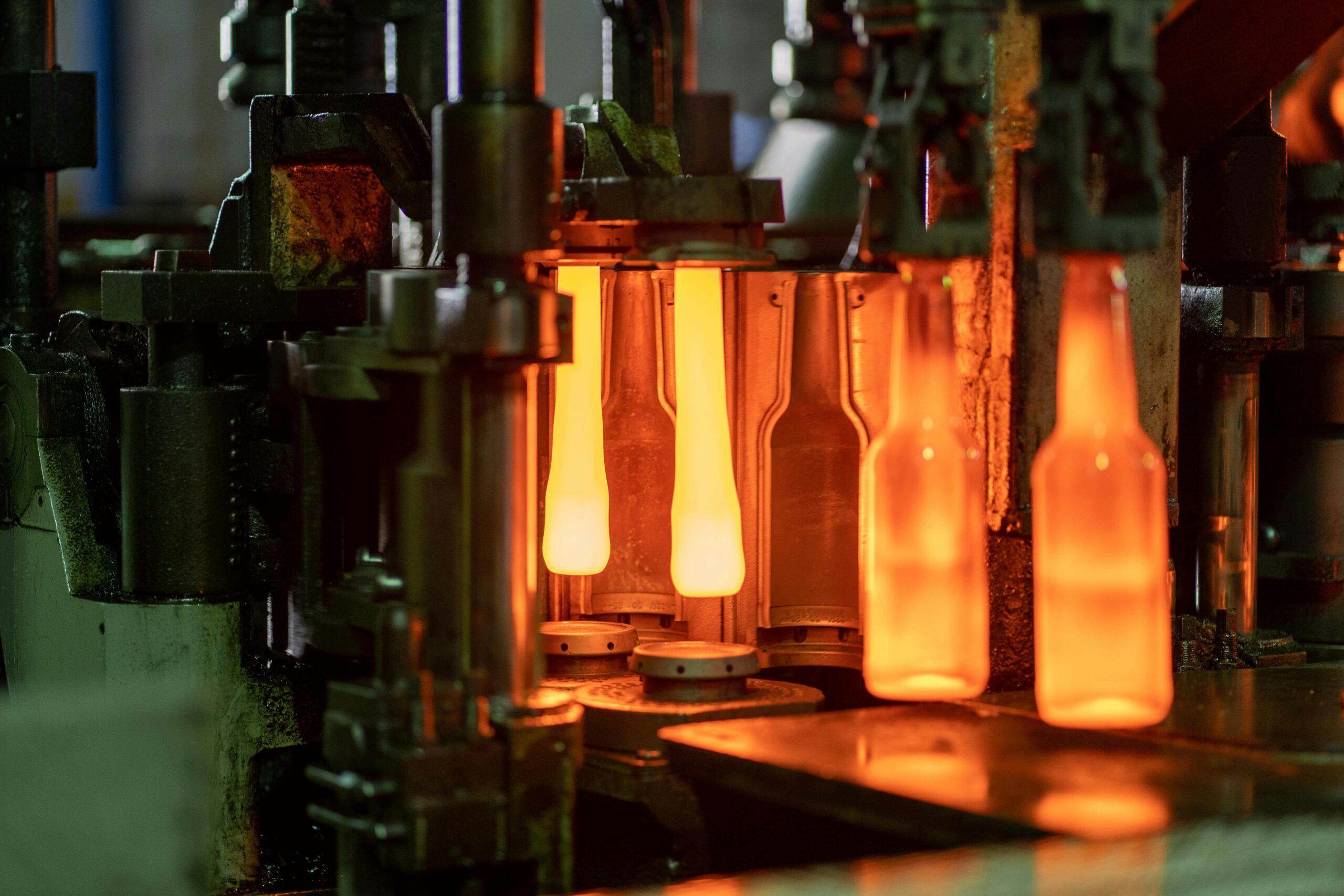 Close-up of molten glass bottles being shaped in a factory machine in Dar es Salaam, Tanzania.