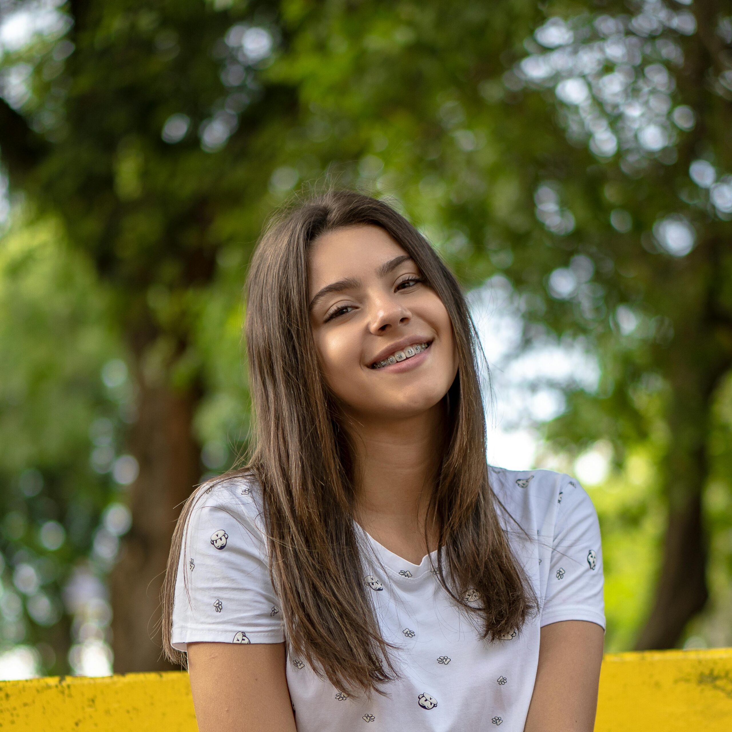 Portrait of a smiling teenage girl outdoors in a park setting.