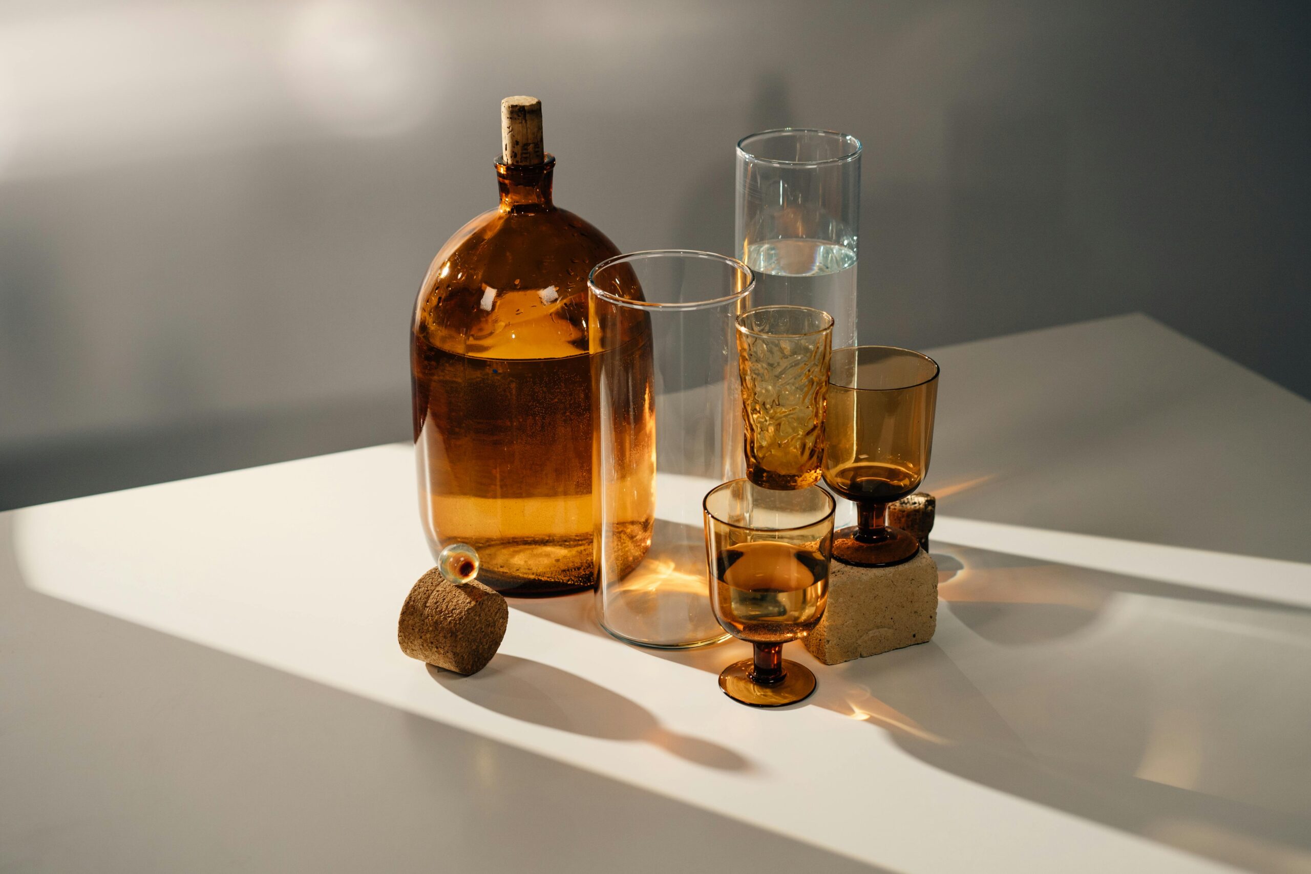 Artistic display of assorted vintage glassware with warm lighting casting natural shadows.